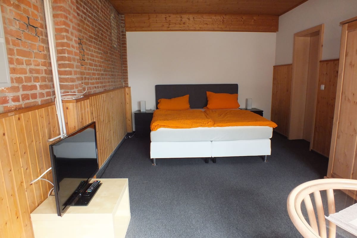 A bedroom with a bed, a TV, and a chair.