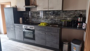 A modern kitchen with a built-in oven, a microwave, and a coffee maker. - Pension Malu wo der Tag ab 6 Uhr mit einem guten Frühstück beginnt (Todenbüttel)