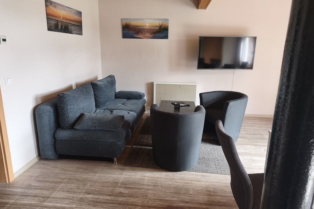A modern living room with a sofa, a coffee table, and a TV mounted on the wall.