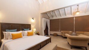 Un dormitorio moderno con una cama grande, cabecera de madera y una zona de estar con sofás.