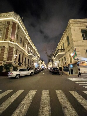 A street view at night with buildings on either side, a pedestrian crossing, and parked cars. - Moss Hotel  (Baku)