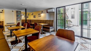 Un restaurant avec des tables en bois et des chaises rouges, un banc à motifs et une vue dégagée grâce à de grandes fenêtres.