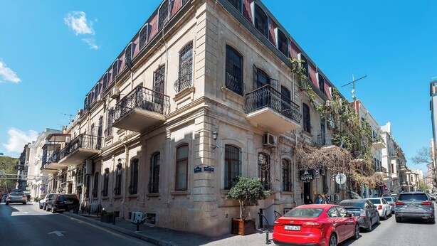 Un immeuble à plusieurs étages, de style architectural classique, doté de balcons et d’une entrée au rez-de-chaussée.