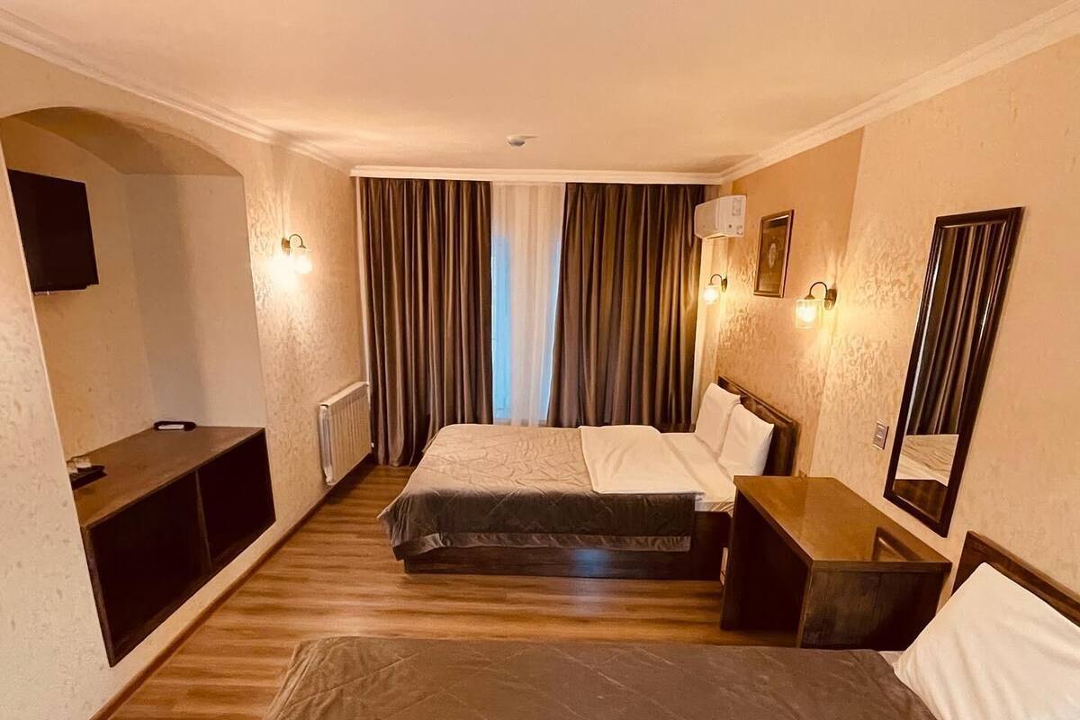 A hotel room with two beds, a TV, a desk, and a mirror.