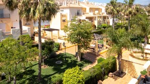 Un quartier résidentiel composé de plusieurs immeubles, de palmiers et d’un jardin bien entretenu.