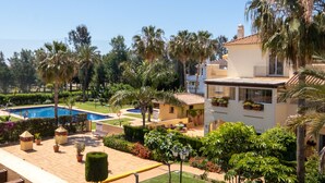 Un complexe hôtelier doté d’une piscine, de palmiers et d’un jardin bien entretenu.