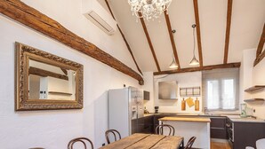 A spacious kitchen with a wooden dining table, chairs, and a chandelier.