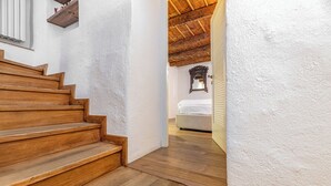 A wooden staircase leading to a bedroom with a wooden ceiling and a bed.