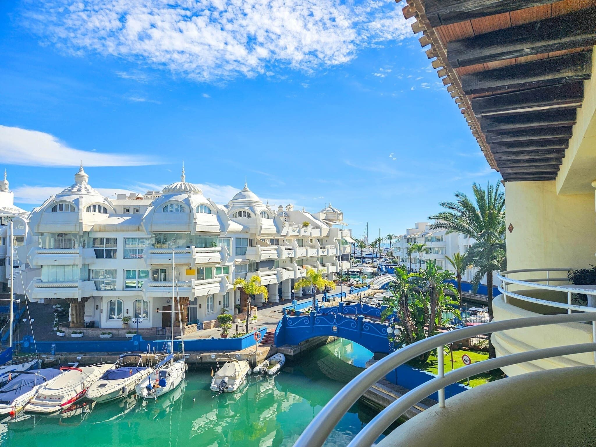 A marina with boats docked, a bridge, and buildings with domed roofs.