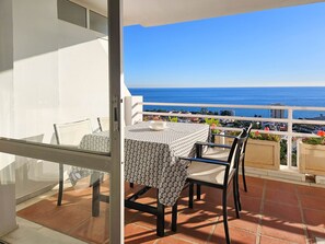 Een balkon met een tafel en stoelen, met uitzicht op de kust.