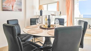 A dining area with a round table, black chairs, and a painting of a woman by the sea. - Two bedroom apartment in Riviera del Sol (Mijas Costa)