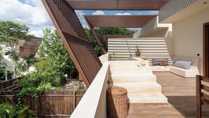 A modern outdoor terrace with a wooden pergola, a seating area with cushions, and a small water feature. - This villa is a 4 bedroom(s), 4 bathrooms, located in Tulum, QR. (Tulum)