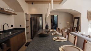 Una cocina moderna con una isla grande, electrodomésticos integrados y una zona de comedor con sofá y sillas.