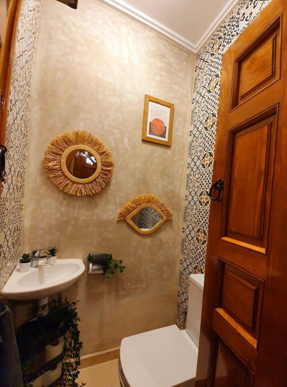 A bathroom with a round mirror, a toilet, and a sink.