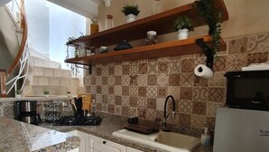 A kitchen with white cabinets, a granite countertop, a stainless steel refrigerator, and a patterned backsplash. - Dar Malika (El Jadida)