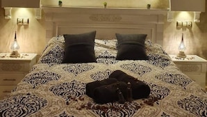 A bed with a patterned bedspread, two pillows, and a bedside table with a lamp. - Dar Malika (El Jadida)