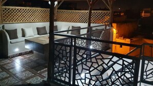 An outdoor seating area with a wooden pergola and a patterned fence. - Dar Malika (El Jadida)