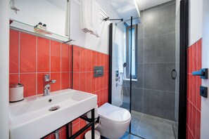 A bathroom with a white sink, red tiles, a glass shower enclosure, and a toilet. - Villa Italic (Antalya)