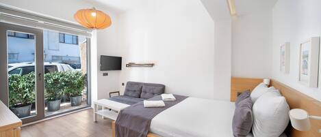 A modern bedroom with a bed, bedside table, and a large window with potted plants.
