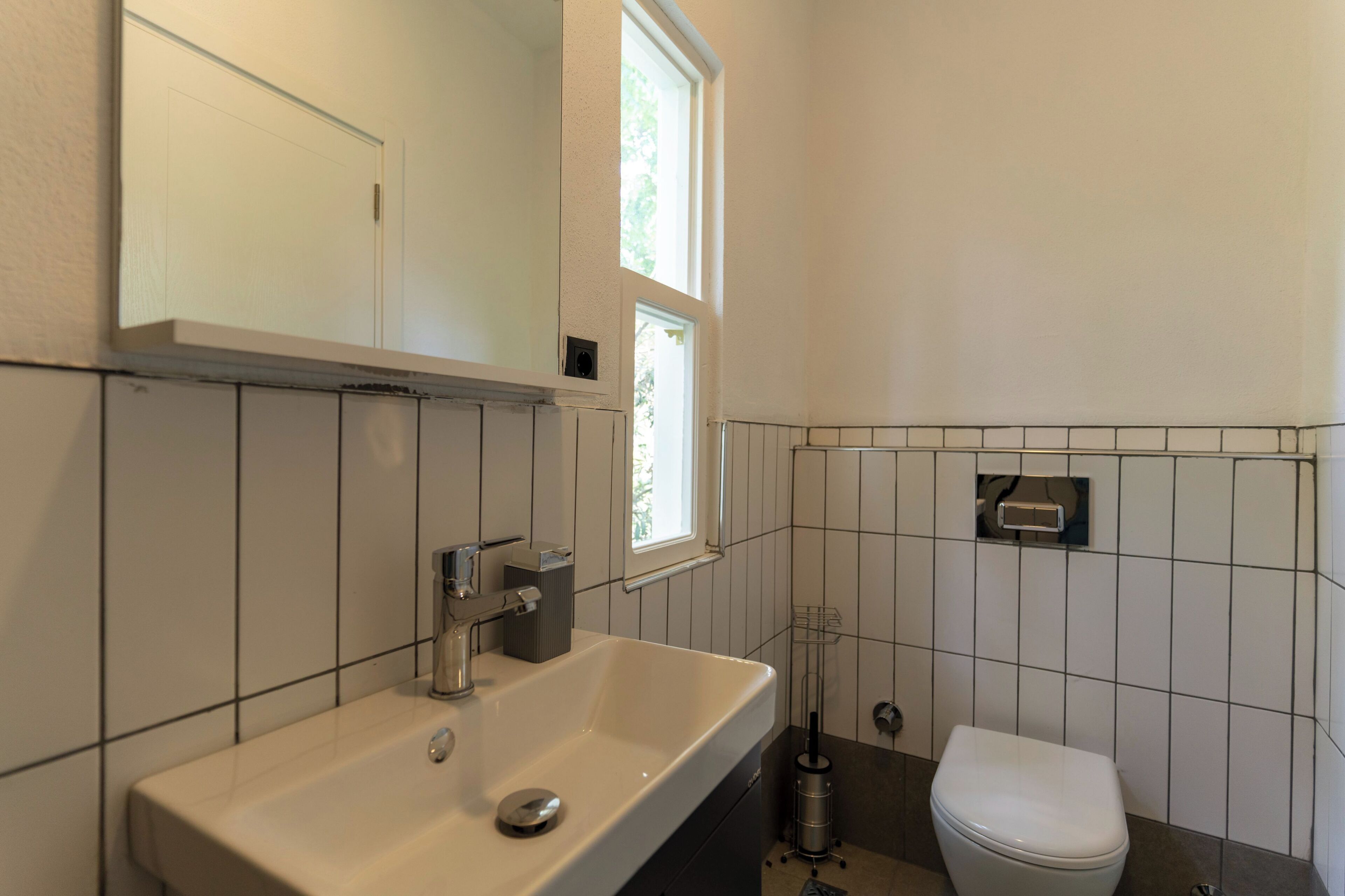 A bathroom with a white sink, a toilet, and a window.