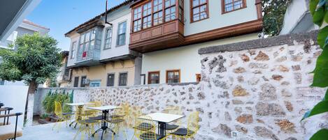 A courtyard with outdoor seating, stone walls, and a building with multiple windows.