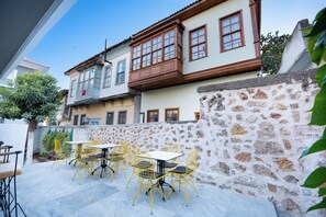 A courtyard with outdoor seating, stone walls, and a building with multiple windows. - Villa Italic (Antalya)