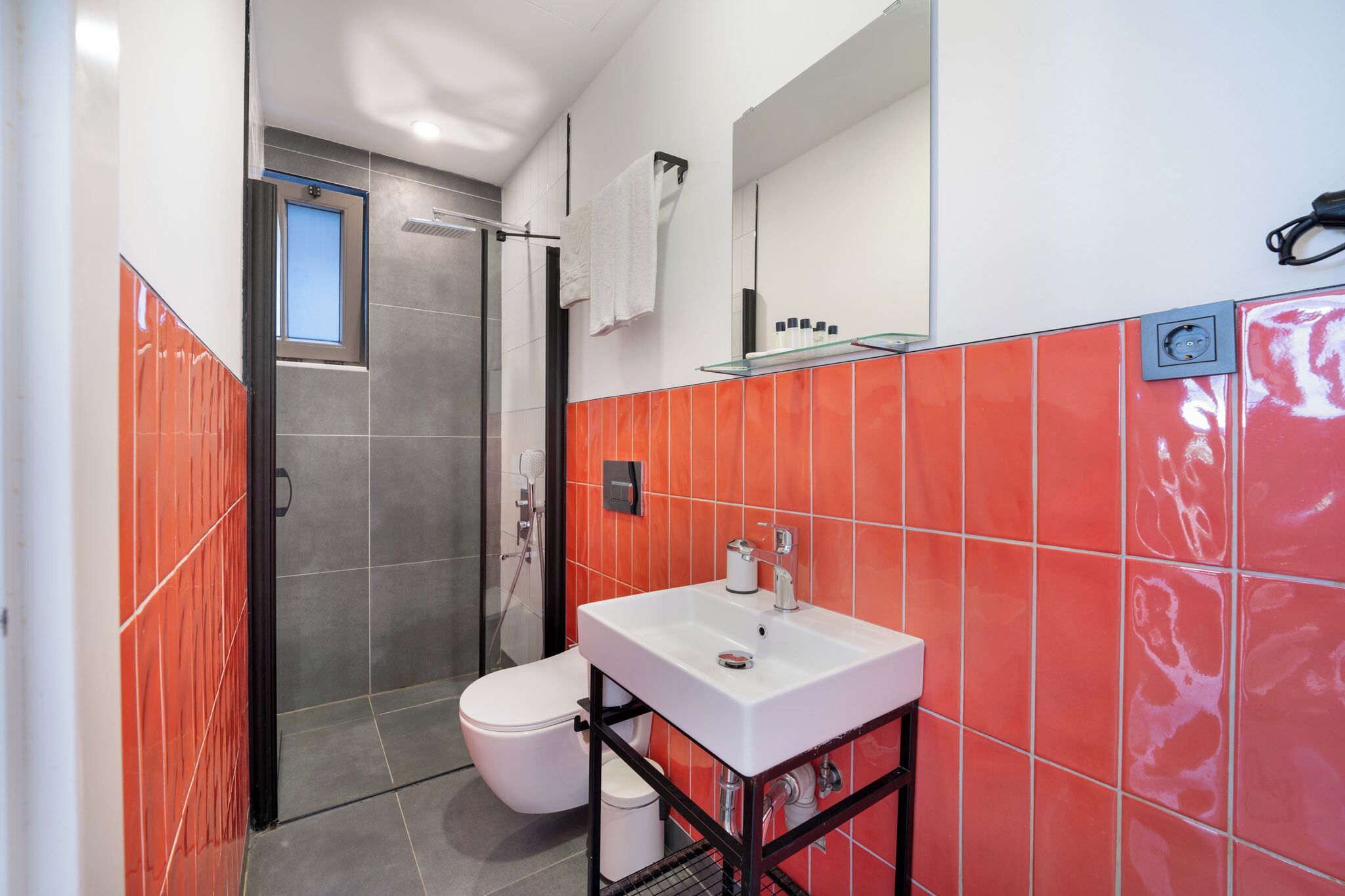 Un baño con un lavamanos blanco, cabina de ducha con mampara de vidrio y un inodoro blanco.