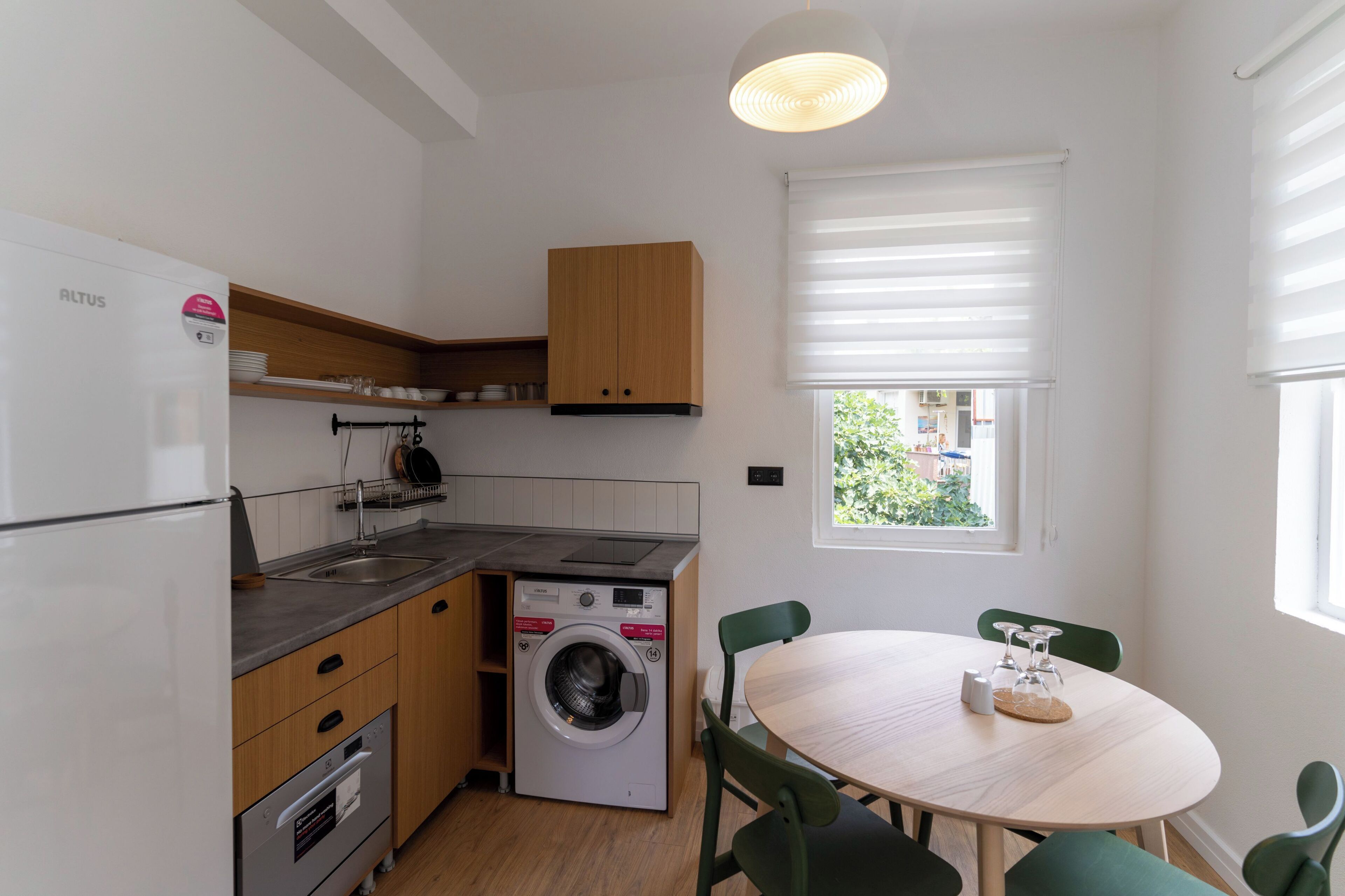 Una cocina compacta equipada con lavadora, refrigerador y comedor con mesa redonda y sillas.