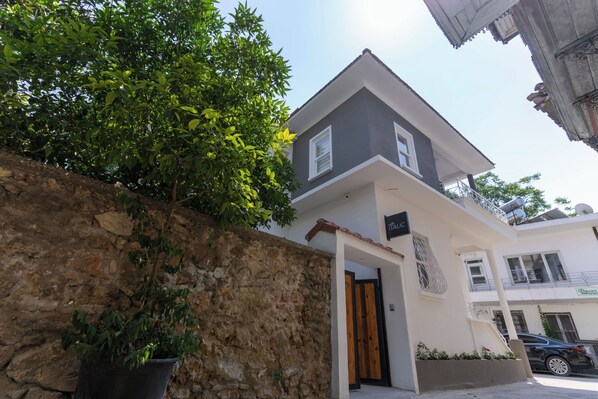 A modern two-story building with a stone wall and a potted plant. - Villa Italic (Antalya)