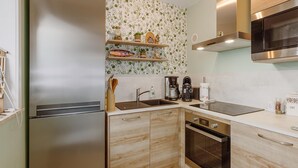 Een moderne keuken met roestvrijstalen apparatuur, houten kastjes en een spatwand met een bladmotief.