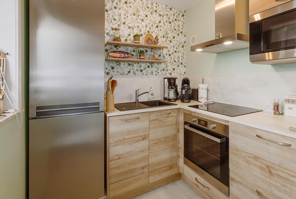 A modern kitchen with stainless steel appliances, wooden cabinets, and a backsplash with a leafy pattern.
