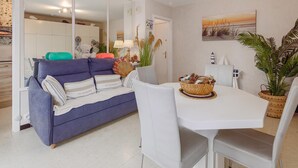 Een moderne woonkamer met een bank, eettafel, stoelen en decoratieve objecten.