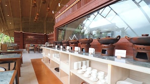 A restaurant with a long counter displaying various pottery items and a view of the outdoors through large windows. - Moritz Hill Borobudur Resorts & Spa (Borobudur)
