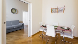 A modern dining area with a table set for two, white chairs, and a red tablecloth. - Four canti luxury apartment  (Palermo)