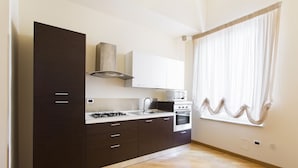 A modern kitchen with dark cabinetry, a gas stove, a microwave, and a built-in oven. - Four canti luxury apartment  (Palermo)