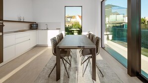 Eine moderne Küche mit weißen Schränken, einer dunklen Arbeitsplatte und einem großen Fenster mit Blick auf einen Garten.