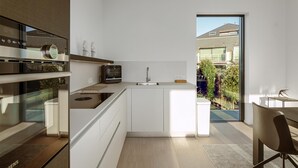 Eine moderne Küche mit Einbauofen, Mikrowelle und Spüle. Ein Essbereich mit Tisch und Stühlen vorhanden.