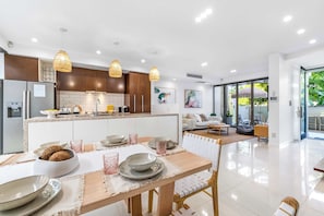 A modern kitchen with wooden cabinets, a central island, and pendant lighting. - Absolute by Khove (Broadbeach)