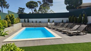A rectangular swimming pool with a clear blue water surface, surrounded by a wooden deck and a grassy area.
