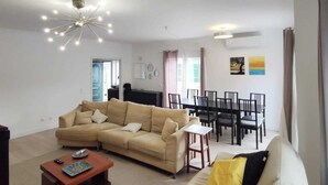 A living room with a beige sofa, a coffee table, and a dining area with a table and chairs.