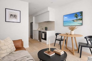A modern apartment with a living room, dining area, kitchen, and a view of a beach.