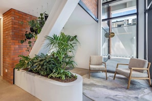A modern interior with a brick wall, a white planter with plants, and two wooden chairs.