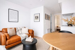 Uma sala de estar moderna com um sofá de couro, uma mesa de jantar redonda de madeira e uma mesa de centro preta.