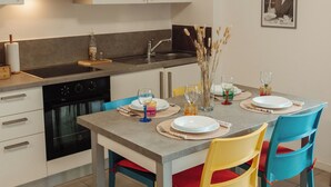 Una cucina moderna con mobili bianchi, forno integrato e zona pranzo con tavolo apparecchiato per quattro persone.