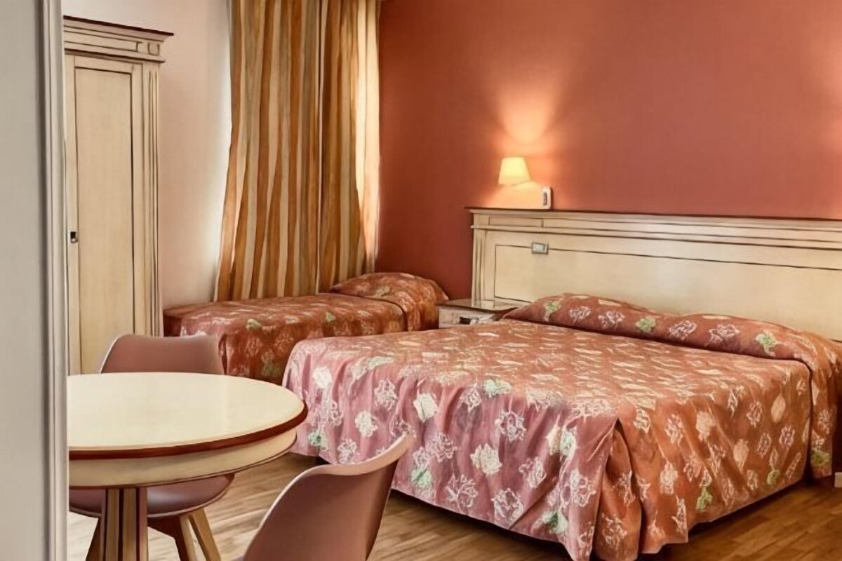 Een hotelkamer met twee bedden, een kleine tafel en een stoel.
