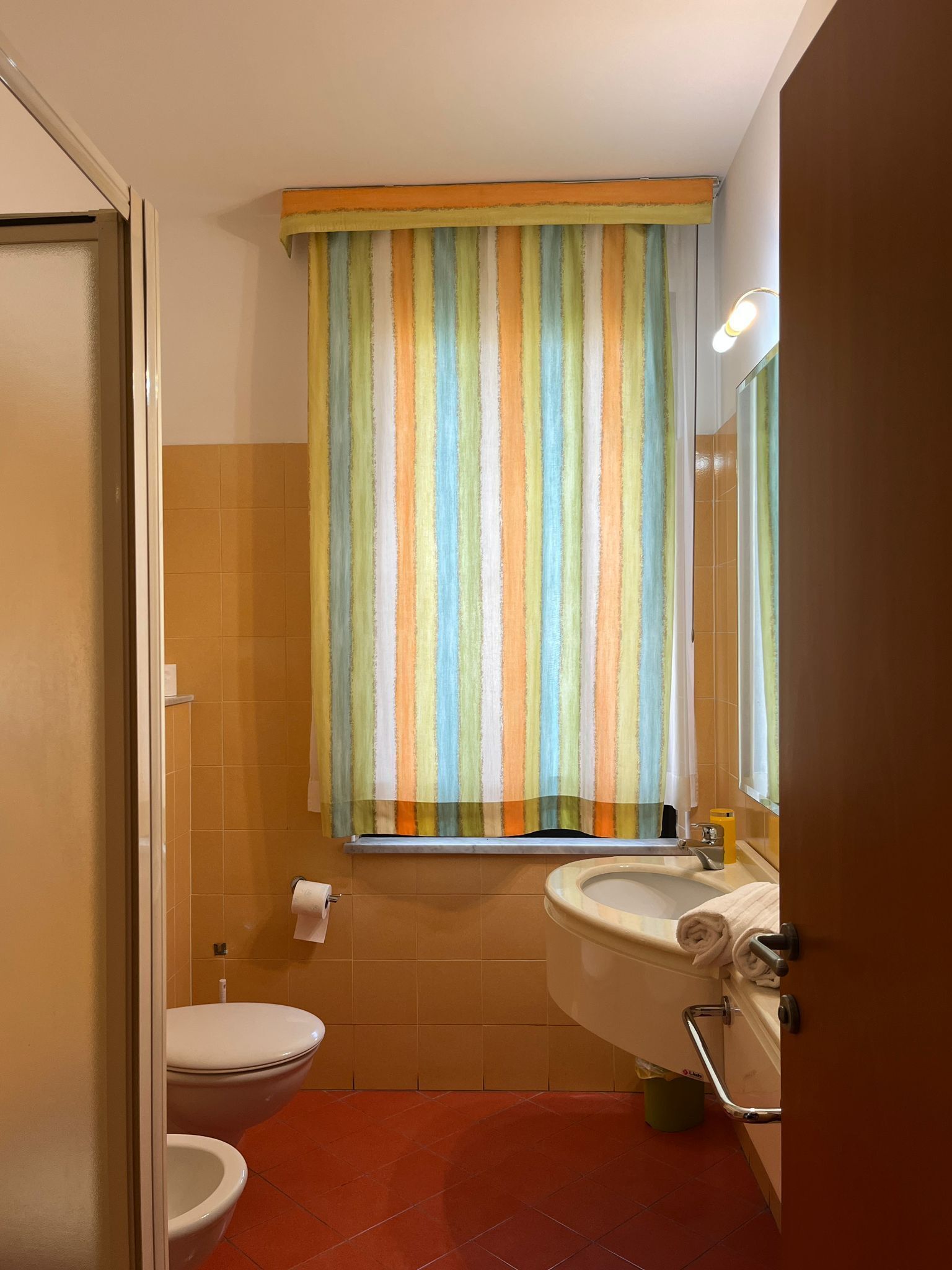 Un baño con cortina de ducha a rayas, inodoro, lavabo y espejo.