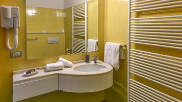 Un baño con paredes amarillas, un lavabo blanco, un espejo, un perchero para toallas y un teléfono.