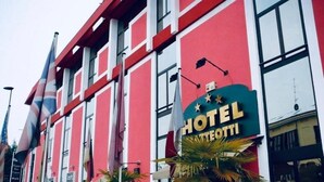 Un hotel con fachada roja, ventanas grandes y un cartel que indica que es un hotel.