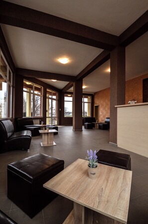 A spacious lobby with a seating area, a reception desk, and large windows offering views. - Hotel Elite Spetema (Bozhurishte)