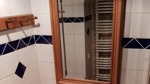 Ett badrum med ett vitt handfat, en träbänkskiva och en spegel med en träram.